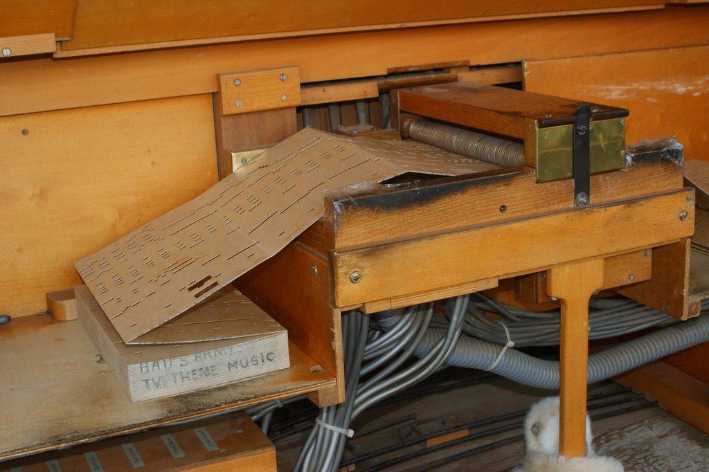 Figure 2 — Close-up of a punched cardboard book passing over the reading keys of a key frame; the sprung key tips and the punched holes are both in view