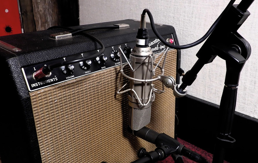 A combo amplifier being close-mic'd with a dynamic microphone — the amp-capture path for a Rhodes, recording the speaker and amp color rather than the clean DI signal. Reference image.