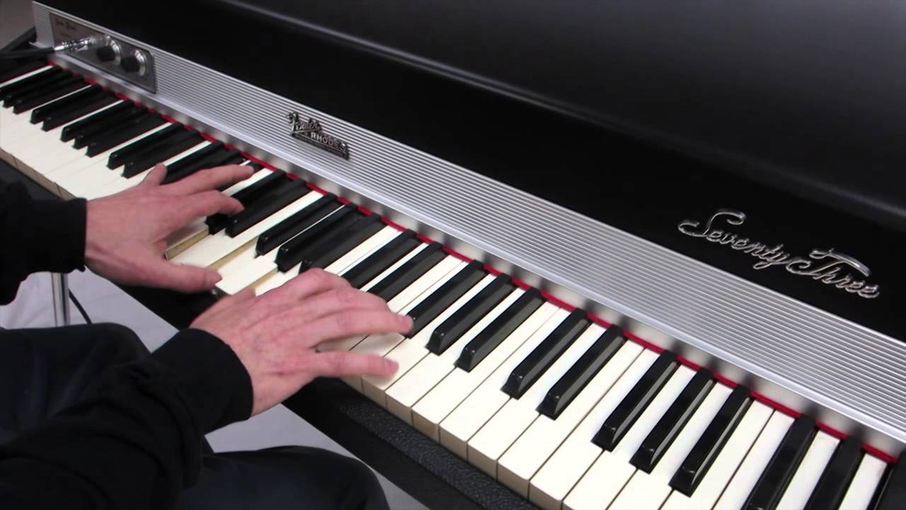 A Fender Rhodes "Seventy Three" being played — hands on the wood-grain keys, the Fender Rhodes badge and "Seventy Three" script visible, illustrating the instrument at the center of the 1970s jazz-…
