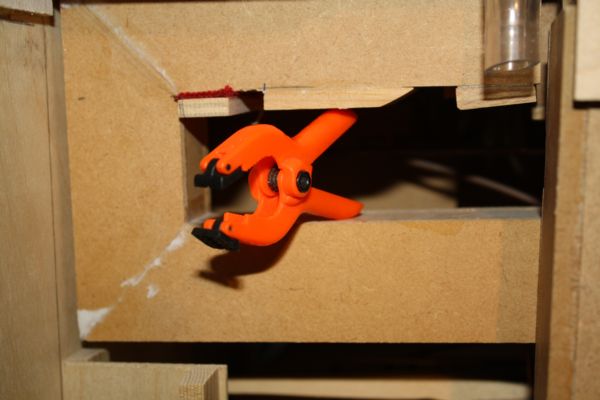 Figure 3 — A wooden flue pipe held square in a right-angle gluing jig with spring clamps while the body seams set.