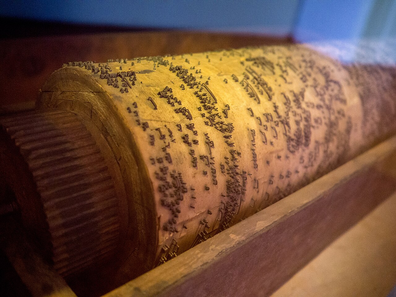 Figure 2 — An antique barrel organ cylinder being re-pinned: the maker maps the original pin pattern before driving replacement pins, treating the pinning as an irreplaceable musical score.