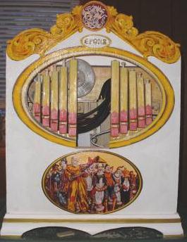 Figure 3 — A decoupage-decorated crank-organ front: a white-painted ply panel with an oval medallion, a name badge, gold-painted end frames and a gap left for the conductor figure