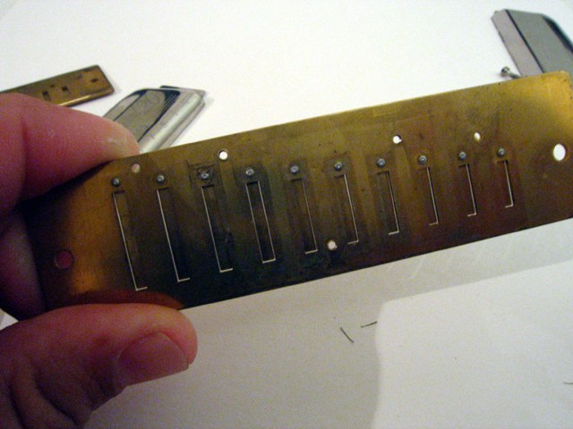 Figure 2 — A melodica free-reed tongue being scratched with a fine file on a hard flat surface to lower its pitch — the middle of the tongue is worked over 3–4 mm, a little at a time
