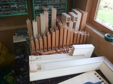 Figure 2 — A rank of flue pipes standing on the wind chest during regulation, the voicer comparing adjacent pipes for even loudness