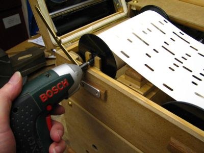 Figure 2 — A cordless screwdriver with a 5 mm hex bit engaging the hex hole of a Raffin take-up spool to power-rewind the roll; a hinged bearing swings clear to give the driver access.