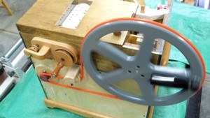 Figure 2 — A heavy Formply/plywood winding-and-driving wheel on a busker organ crankshaft (jsart129, David Briggs); its rotational inertia makes it a modest flywheel that smooths the lumpy feeder torque, and …